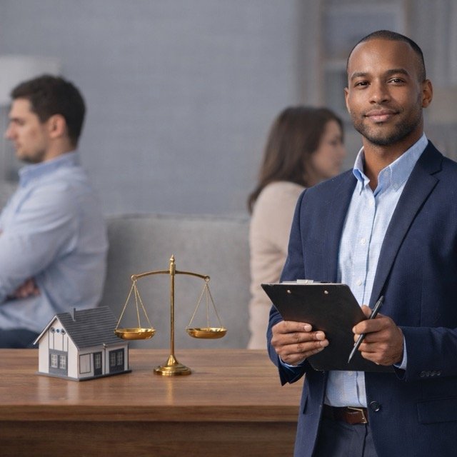 Professional real estate appraiser conducting a divorce appraisal with a couple, showing a home model and balance scale used to determine fair property value.